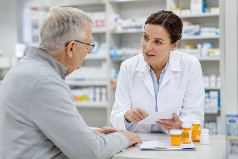 AI-generated image of an older man consulting with a pharmacist about medications at a pharmacy counter.