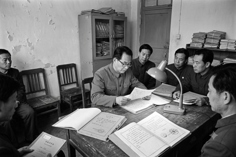 AI-generated black-and-white image of Chinese court officials in a modest 1980s government office reviewing old case files and documents as part of a wrongful conviction investigation.