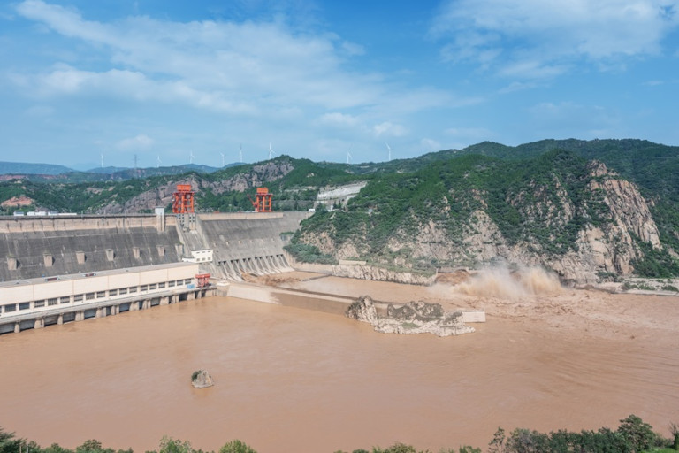 Massive concrete dam discharging muddy brown water, Henan province, China. 