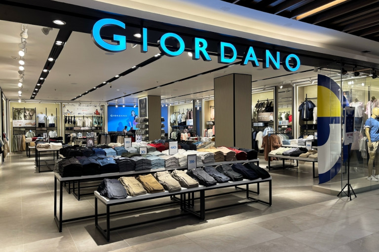 Giordano store displaying neatly folded garments inside a brightly lit mall.