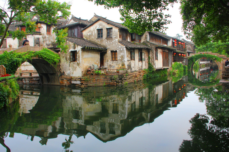 Houses lining the canals running through Zhouzhuang cast reflections on the water.