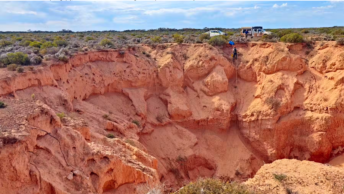 One of the field team abseils into a collapse feature to record the sediment and reach the underlying cave system to measure the thickness and any disturbance of the geology.