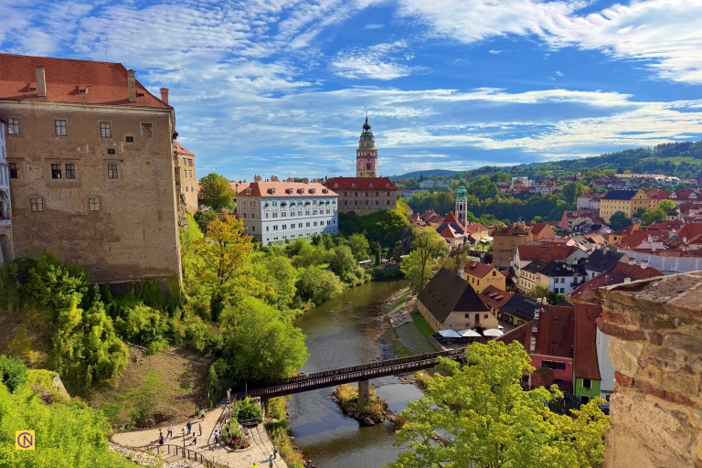 Český Krumlov's red rooftops line the scenic Vltava River against a backdrop of lush green hills.