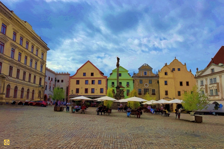 Colorful historic façades and outdoor cafés bring life to Český Krumlov’s charming cobblestone square.