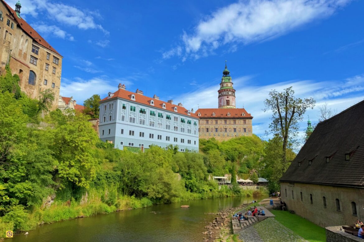 The red rooftops of Český Krumlov line the scenic Vltava River against a backdrop of lush green hills.