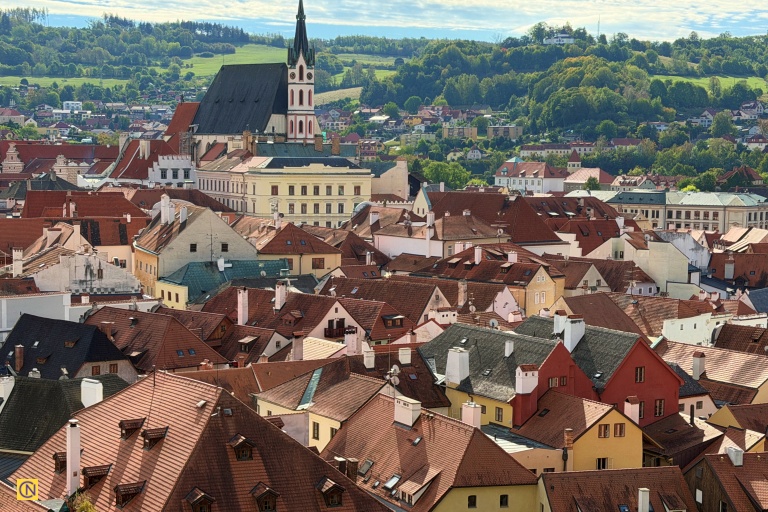 A sea of red-tiled rooftops surrounds the Gothic church spire in Český Krumlov’s picturesque historic center.
